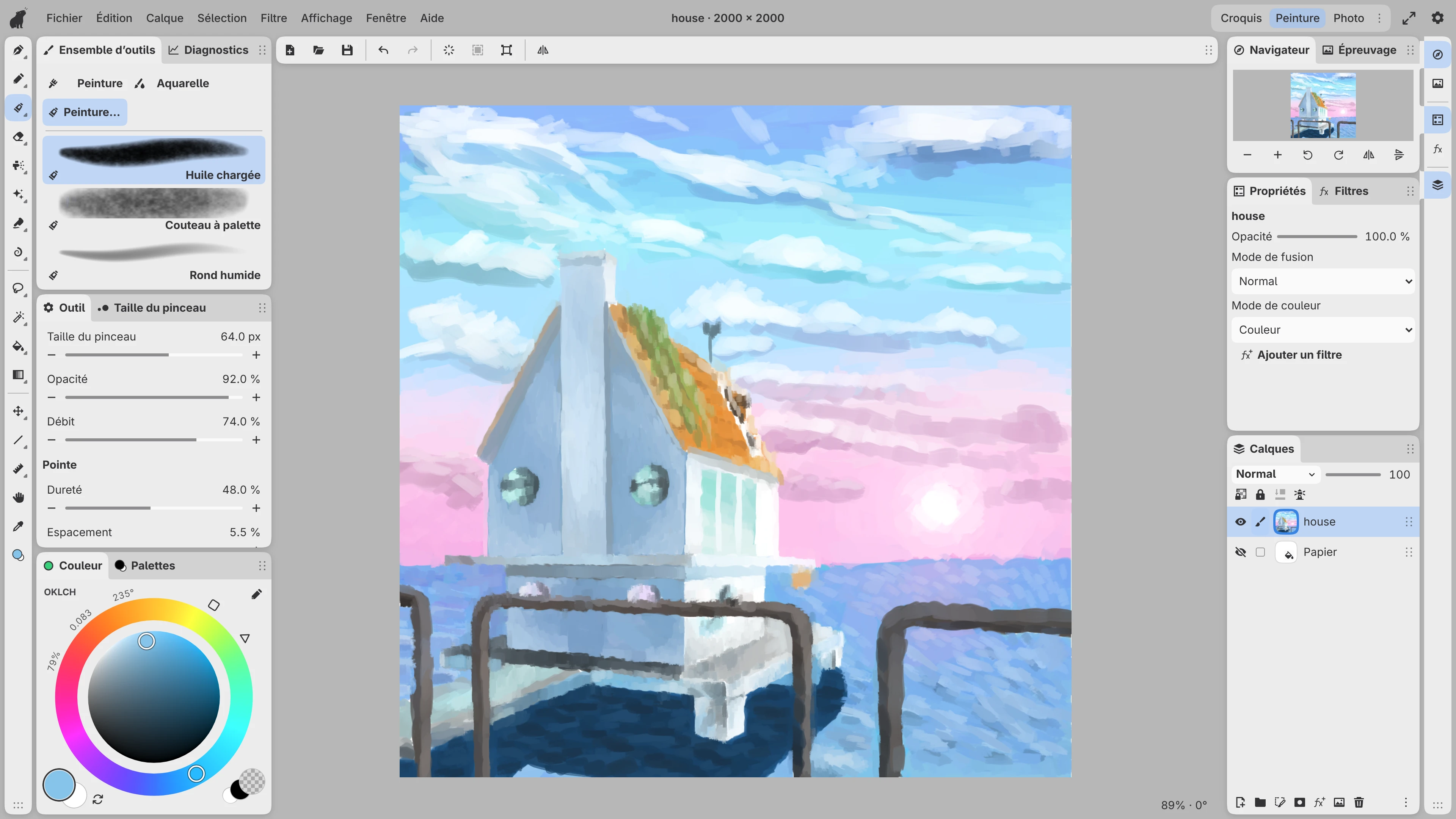 Une peinture à l'huile d'une maison au bord de la mer au coucher du soleil dans l'espace de travail Paint, avec des pinceaux, des couleurs et des calques à côté de la toile.
